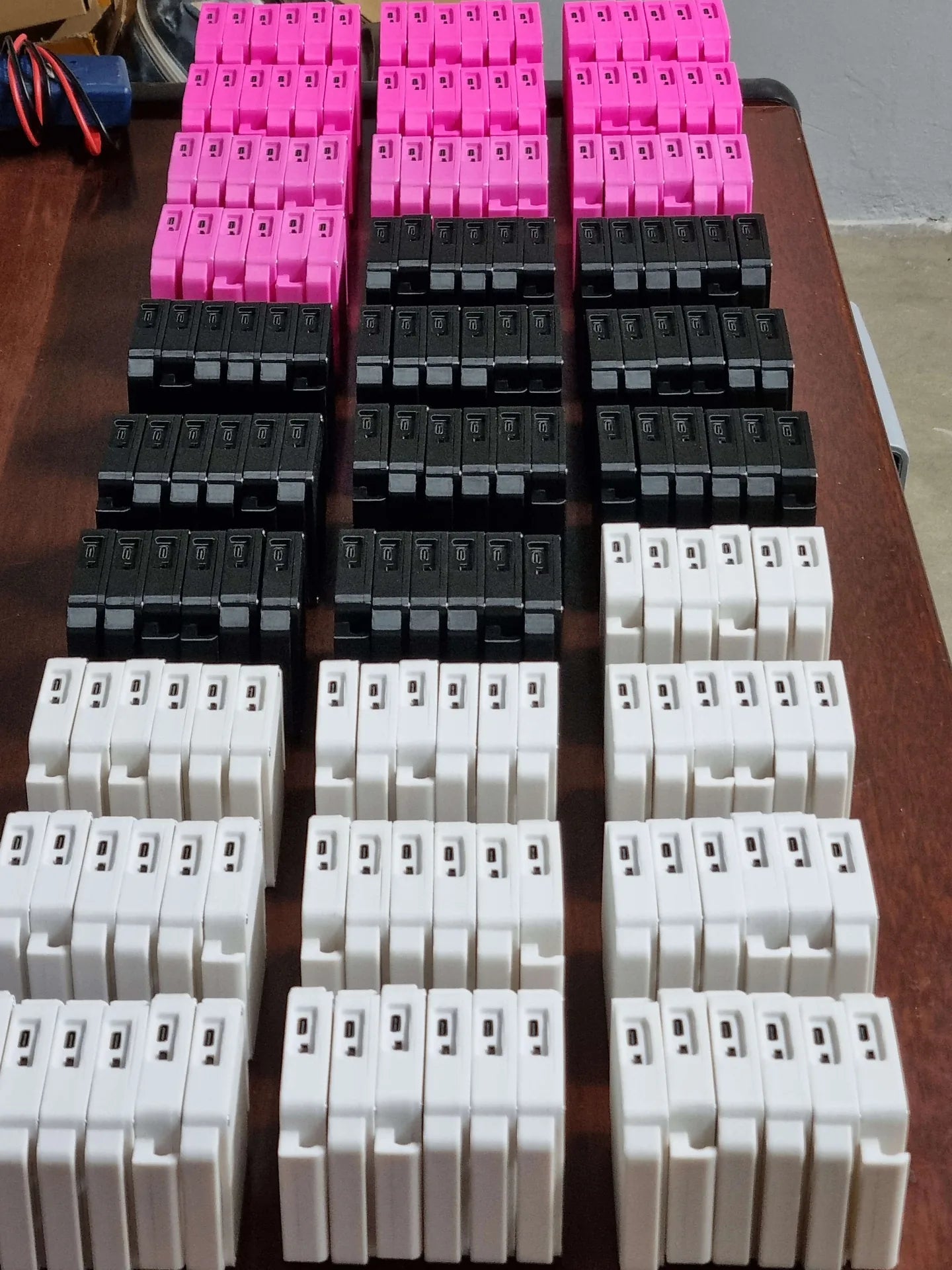 Trackers VEX rosa, preto e branco enfileirados sobre a bancada, prontos para envio.